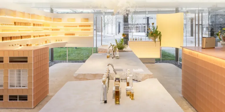 美妆品牌营销案例中的香氛门店陈列，多排瓶装产品置于灯光展架与大理石台面